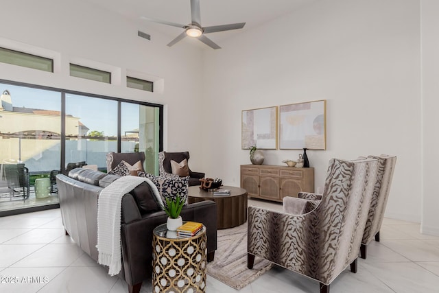 tiled living room with ceiling fan and a towering ceiling