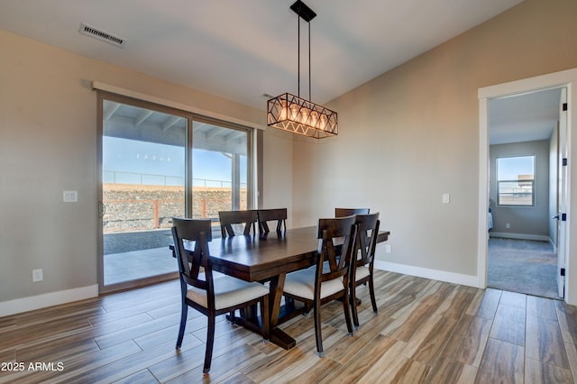 dining space featuring visible vents, baseboards, wood finished floors, and a chandelier