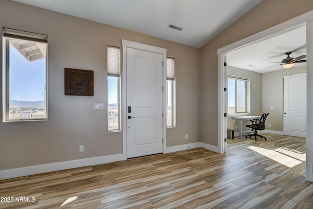 foyer entrance with visible vents, light wood-style flooring, a ceiling fan, and baseboards