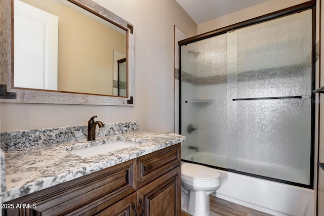 full bathroom with wood finished floors, toilet, vanity, and shower / bath combination with glass door