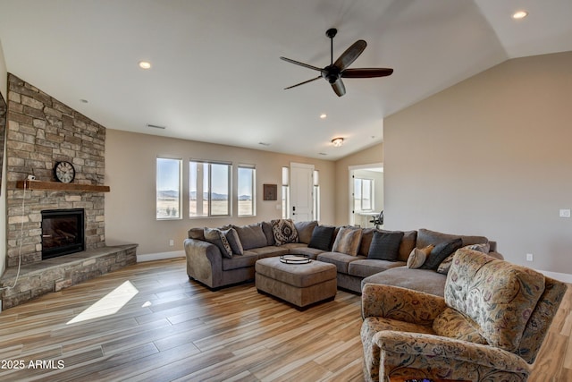 living room featuring a stone fireplace, lofted ceiling, light wood-style floors, and a wealth of natural light