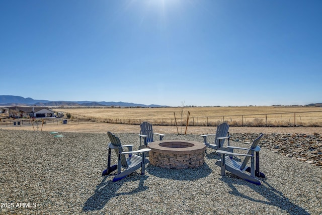 view of yard with a rural view, a mountain view, a fire pit, and fence