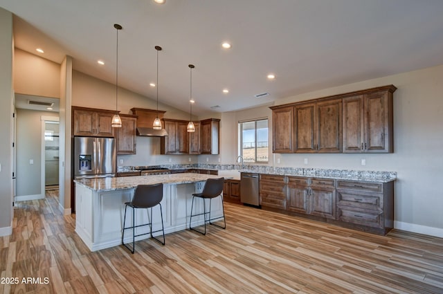 kitchen with a kitchen bar, light wood-style flooring, appliances with stainless steel finishes, and a center island