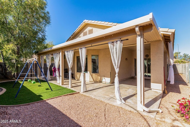 back of house featuring a playground and a patio area