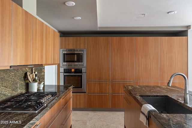 kitchen with sink, backsplash, stainless steel appliances, and dark stone counters