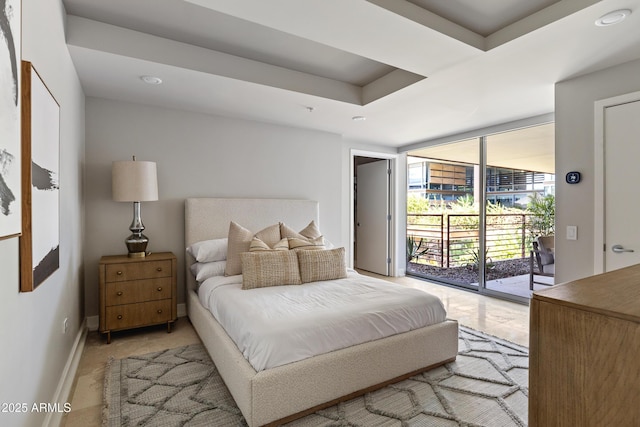 bedroom with access to exterior, floor to ceiling windows, and a raised ceiling