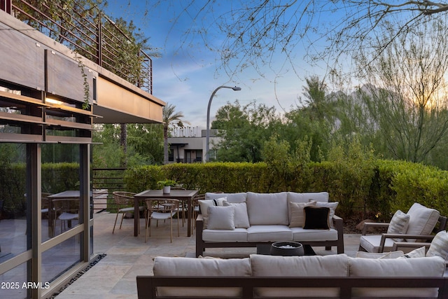 patio terrace at dusk with an outdoor living space and a balcony