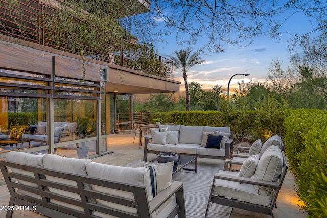 patio terrace at dusk with a balcony and an outdoor hangout area