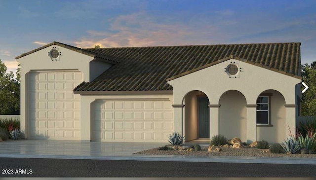 mediterranean / spanish-style home featuring a garage, driveway, and stucco siding