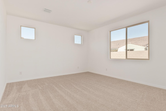 carpeted empty room featuring baseboards and visible vents