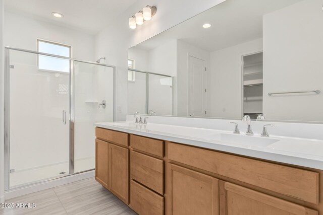 full bathroom featuring a sink, a closet, a stall shower, and double vanity