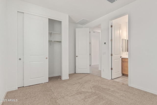 unfurnished bedroom featuring baseboards, a closet, light carpet, and visible vents