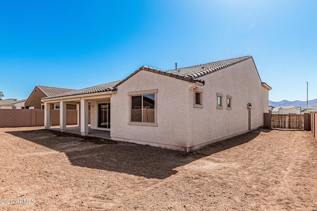 rear view of house with a patio area, stucco siding, a tile roof, and a fenced backyard