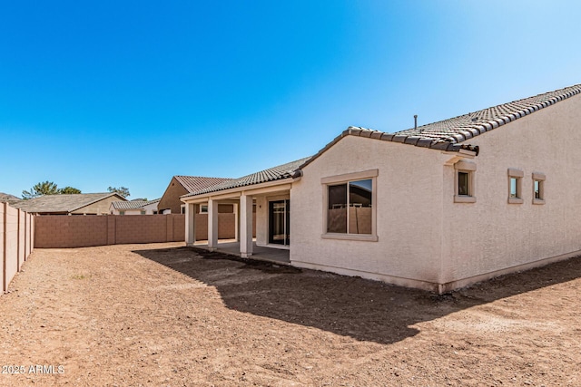 back of property with a patio area, a tile roof, a fenced backyard, and stucco siding