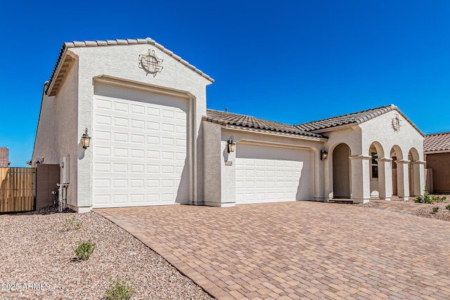 garage with decorative driveway and fence