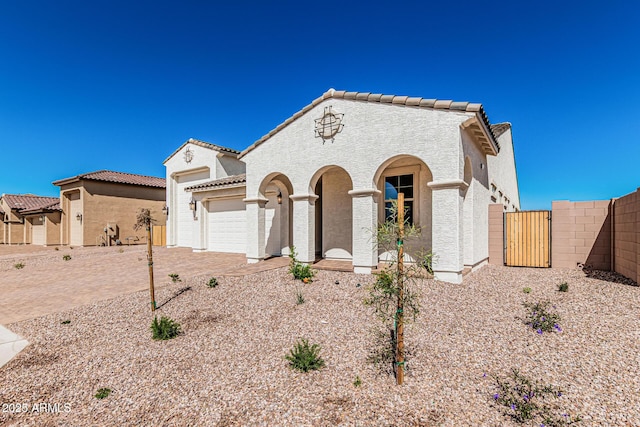 mediterranean / spanish house featuring stucco siding, a tiled roof, decorative driveway, and a garage