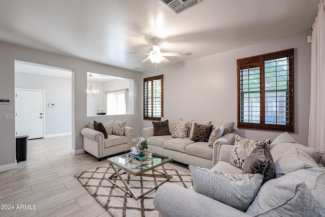 living room with ceiling fan with notable chandelier and light hardwood / wood-style floors