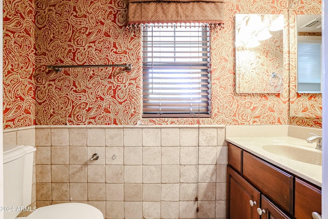 bathroom with tile walls, toilet, and vanity