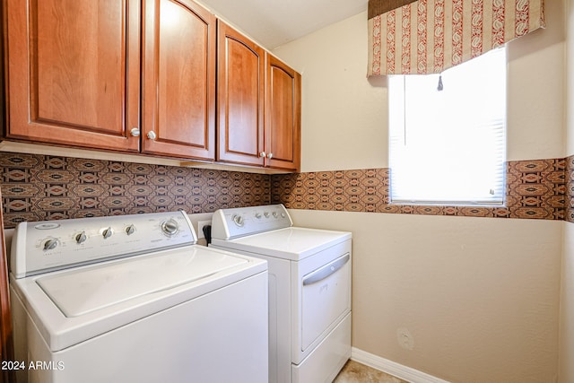 laundry room with washing machine and clothes dryer and cabinets