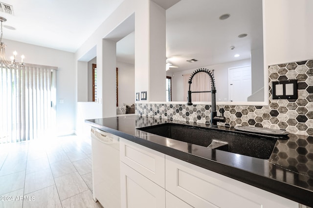 kitchen featuring a notable chandelier, backsplash, decorative light fixtures, white dishwasher, and white cabinets