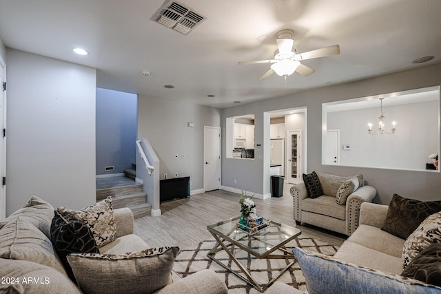 living room with ceiling fan with notable chandelier and light wood-type flooring