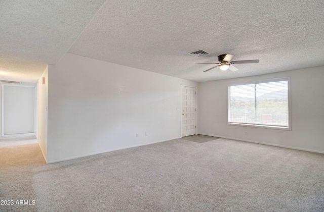 spare room with ceiling fan, light colored carpet, and a textured ceiling