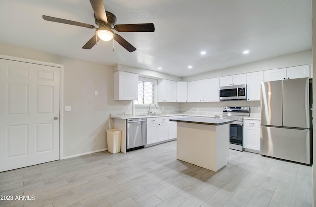 kitchen featuring sink, appliances with stainless steel finishes, white cabinetry, light hardwood / wood-style floors, and a kitchen island