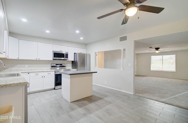 kitchen featuring sink, light hardwood / wood-style flooring, appliances with stainless steel finishes, a kitchen island, and white cabinets