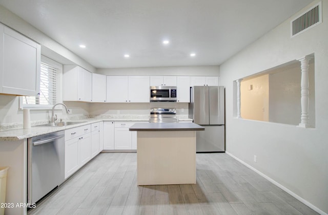 kitchen featuring sink, light hardwood / wood-style flooring, appliances with stainless steel finishes, a center island, and white cabinets