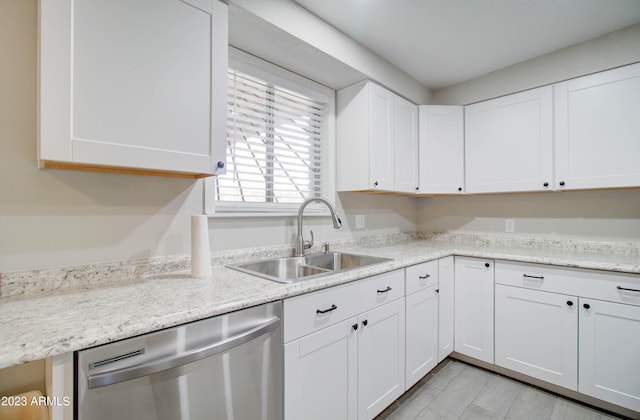 kitchen with white cabinetry, light stone countertops, sink, and stainless steel dishwasher