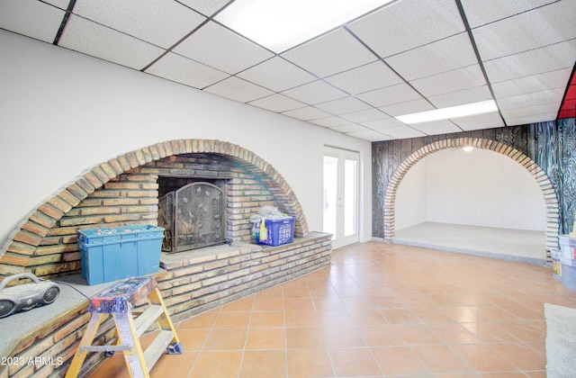 unfurnished living room featuring tile patterned flooring, a fireplace, and a paneled ceiling