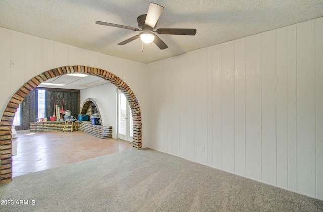 carpeted empty room featuring ceiling fan and a textured ceiling