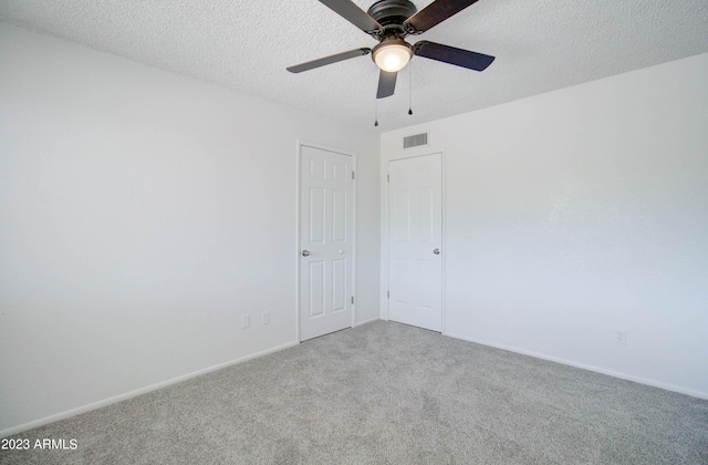 unfurnished room with ceiling fan, light colored carpet, and a textured ceiling