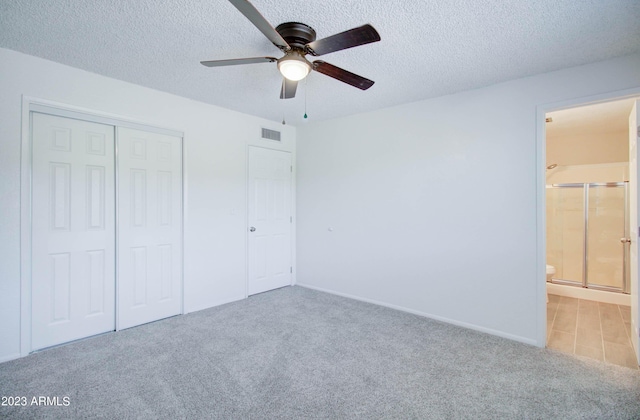 unfurnished bedroom featuring connected bathroom, light carpet, a textured ceiling, and a closet