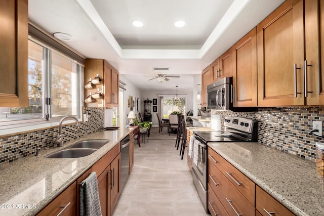 kitchen with ceiling fan, sink, stainless steel appliances, light stone counters, and backsplash