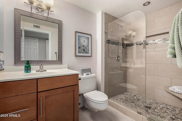 bathroom with tiled shower, vanity, and toilet