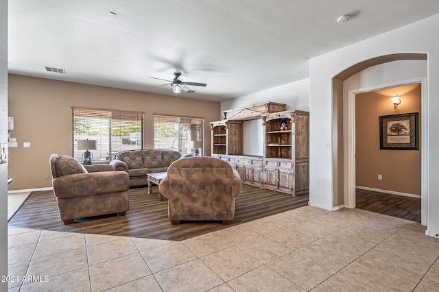 tiled living room featuring ceiling fan and a textured ceiling