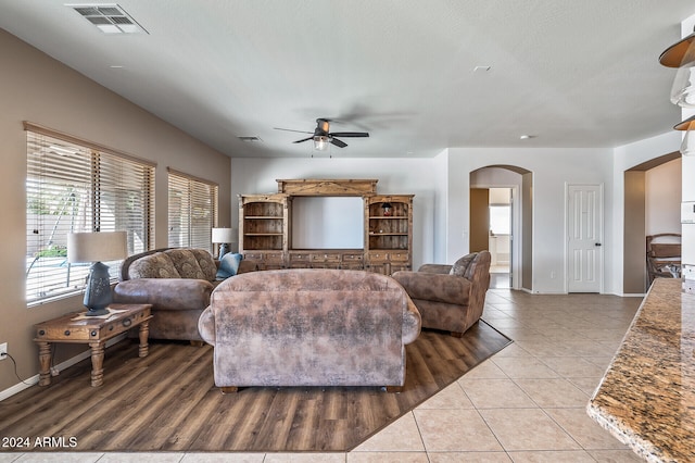 living room featuring ceiling fan, a textured ceiling, and light tile patterned flooring