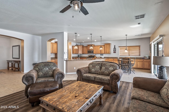 living room with sink, ceiling fan, a textured ceiling, and light hardwood / wood-style flooring