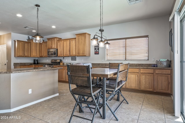 kitchen with appliances with stainless steel finishes, light tile patterned flooring, and pendant lighting