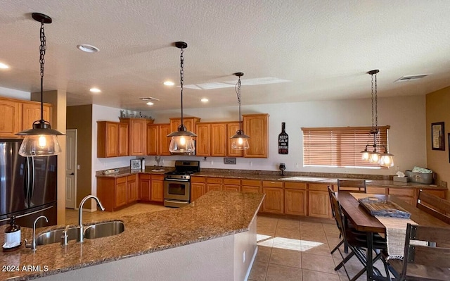 kitchen featuring a textured ceiling, stainless steel appliances, hanging light fixtures, and sink