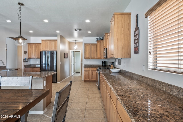 kitchen featuring dark stone countertops, stainless steel appliances, sink, and pendant lighting