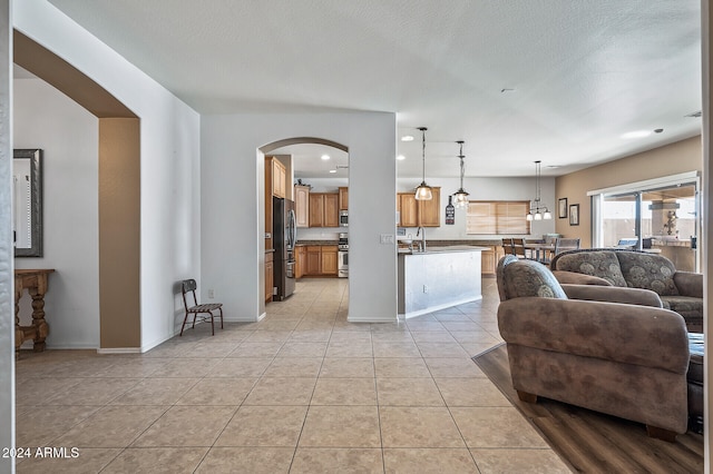 living room featuring sink, a textured ceiling, and light tile patterned floors