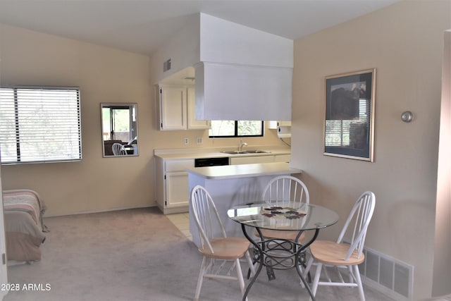 kitchen with visible vents, vaulted ceiling, light countertops, white cabinetry, and a sink