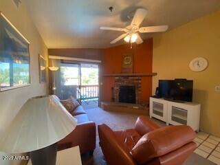 tiled living area featuring lofted ceiling, a fireplace, and a ceiling fan