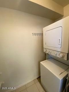 washroom featuring laundry area, baseboards, stacked washer / drying machine, and light tile patterned flooring