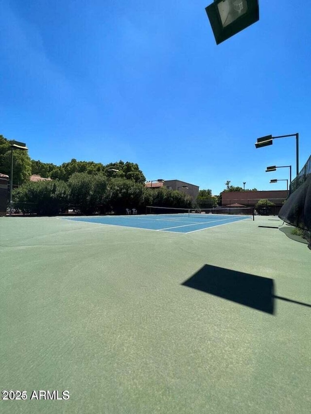 exterior space with a tennis court and fence