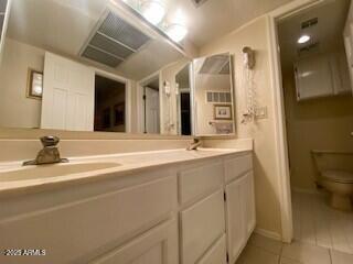 full bathroom featuring double vanity, toilet, a sink, baseboards, and tile patterned floors