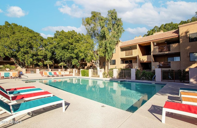 pool with a patio and fence