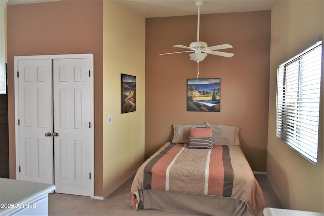 bedroom featuring a towering ceiling, baseboards, a closet, and light colored carpet